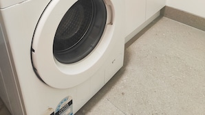 Eine Samsung Waschmaschine mit Frontlader in einem Waschraum, darüber ein Waschbecken.