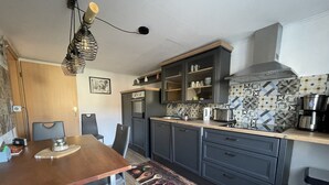 Eine kleine Küche mit dunklen Schränken, einer Holz Arbeitsplatte und einer gemusterten Spritzschutzwand.