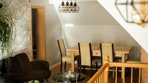 Ein Essbereich mit einem Holztisch und Stühlen, einer schwarzen Couch und einer hängenden Leuchte.