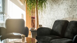 Ein modernes Wohnzimmer mit einer schwarzen Ledersofa, einem Glastisch und einer Topfpflanze.