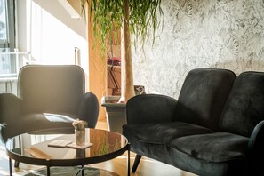 Ein modernes Wohnzimmer mit einer schwarzen Ledersofa, einem Glastisch und einer Topfpflanze.