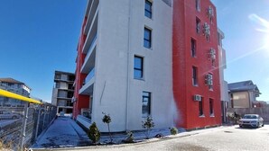A multi-story building with a white and red facade, featuring balconies and a clear sky. - BBC Apartments (Navodari)