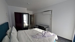 A hotel room with a bed, a desk, a wardrobe, and an air conditioning unit. - BBC Apartments (Navodari)