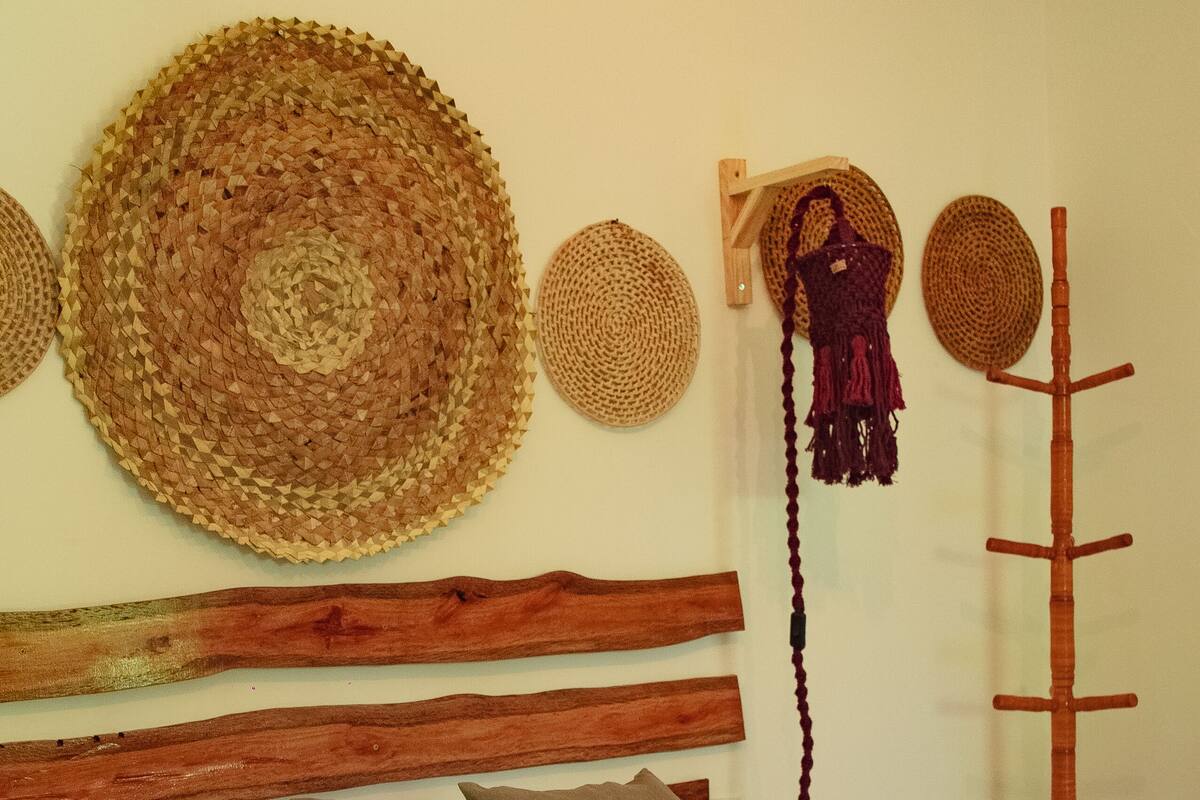 A bedroom with a wooden headboard, a patterned bedspread, and several woven baskets on the wall.