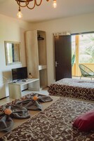 Un dormitorio con dos camas, televisión, armario y balcón con una silla.