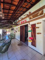 Un área de patio techada con techo de madera, sillas verdes y piso de baldosas.