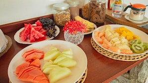 Ein Tisch mit verschiedenen Früchten und Snacks, darunter Wassermelone, Trauben, Bananen und Orangen.