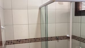 Ein kleines Badezimmer mit Fliesen, einer Glasdusche, einer Toilette und einem Waschbecken.