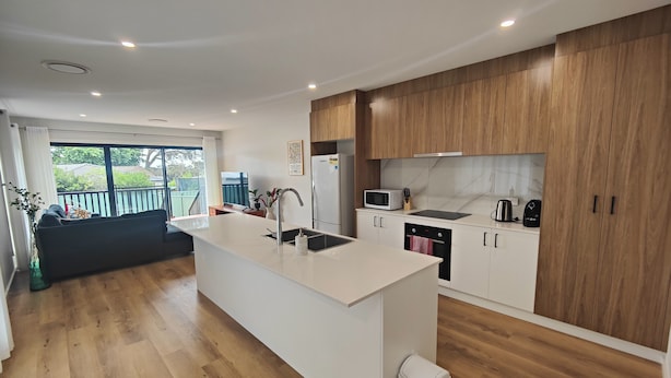 Una cocina moderna con una isla central, armarios de madera y vistas al exterior.