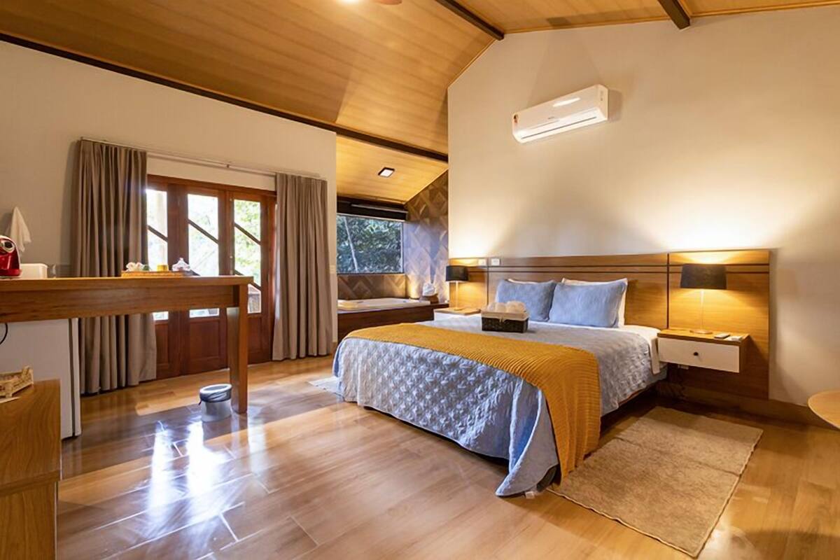 A bedroom with a bed, bedside tables, a desk, and a window with curtains.