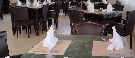 Un salón de conferencias con una mesa de mármol verde, servilletas blancas y dos saleros.