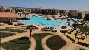 Een resort met een groot centraal zwembad, ligbedden en uitzicht op zee.
