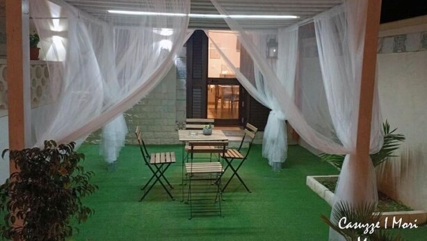 An outdoor patio with a table and chairs, surrounded by white drapes and artificial grass.