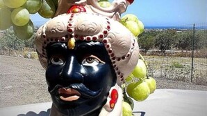 A decorative sculpture with a face and a headpiece adorned with grapes and red berries.