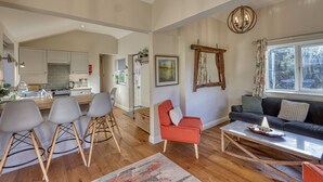 Un salón amplio con sofá, una mesa de centro y una zona de comedor con sillas, y una cocina al fondo.