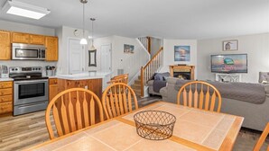 A modern kitchen with wooden cabinets, a built-in microwave, and a dining area with a table and chairs.