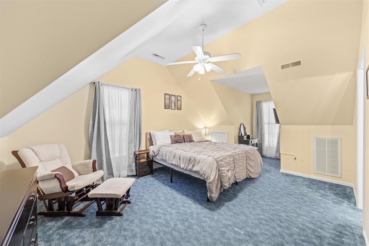 Quarto com cama, cadeira, escrivaninha e ventoinha no teto.