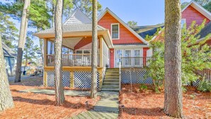 A wooden deck leading to a house with a covered porch and a fenced yard.