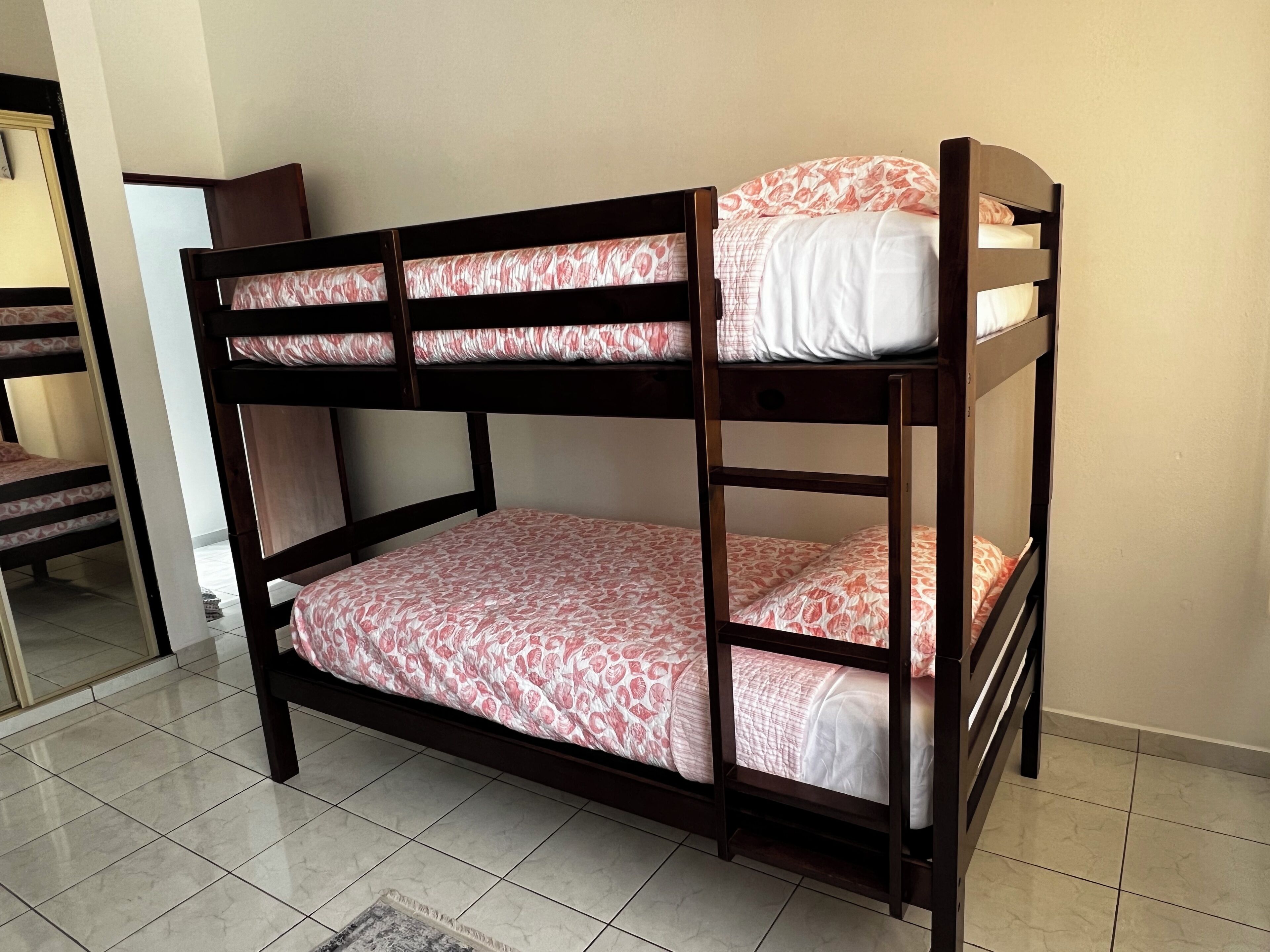 Una cama litera con dos niveles, cada uno con una colcha estampada.