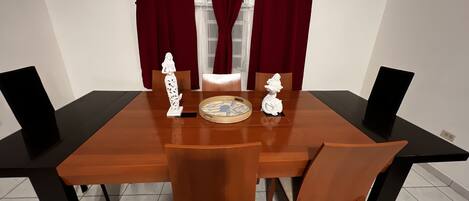 A dining table with four chairs, a decorative plate, and two white figurines.