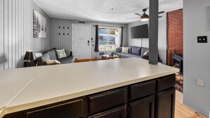 A modern kitchen with a large island, wooden cabinets, and a view to a balcony. - Ski-In/Ski-Out on Chair 8 | Cozy Condo Sleeps 6 (Brian Head)