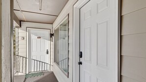 A covered walkway leading to a white door with a number plate, a glass door, and a metal railing. - Ski-In/Ski-Out on Chair 8 | Cozy Condo Sleeps 6 (Brian Head)