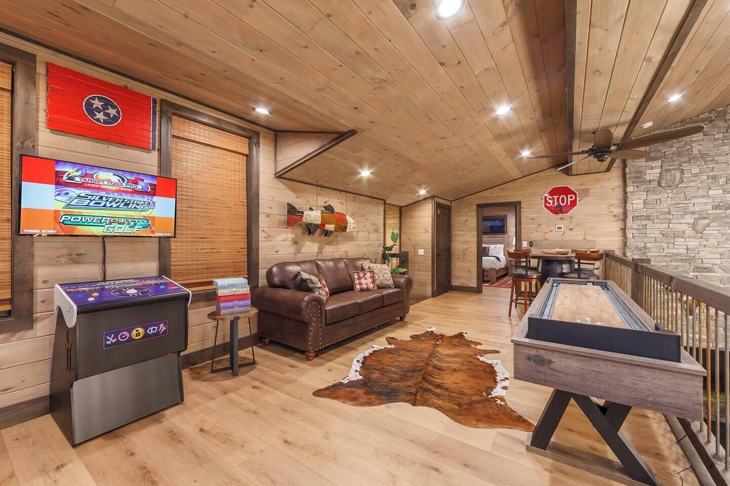 Una habitación acogedora con techo de madera, un sofá de cuero, un dardo y una mesa de billar.
