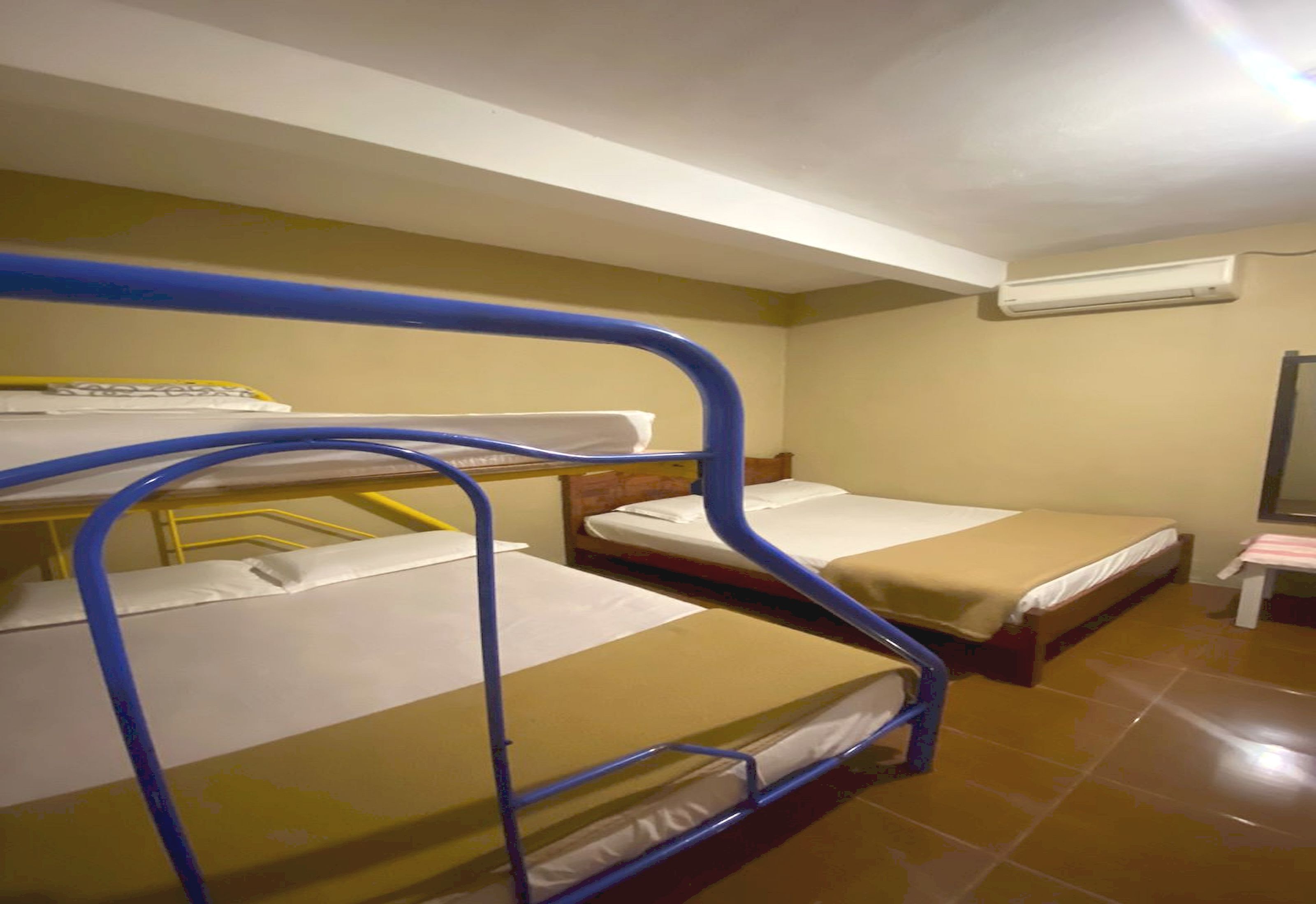 Ein Schlafsaalzimmer mit Etagenbetten, einem kleinen Tisch und einer Klimaanlage an der Wand.