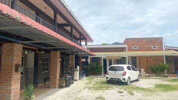 A two-story building with a covered porch and a white car parked in front.