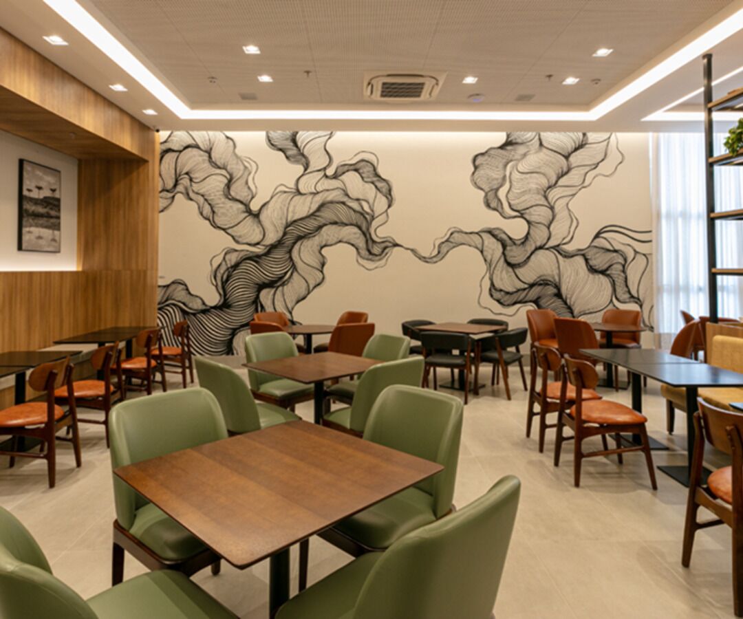 A restaurant with wooden tables and chairs, a mural on the wall, and a wooden panel on the left.
