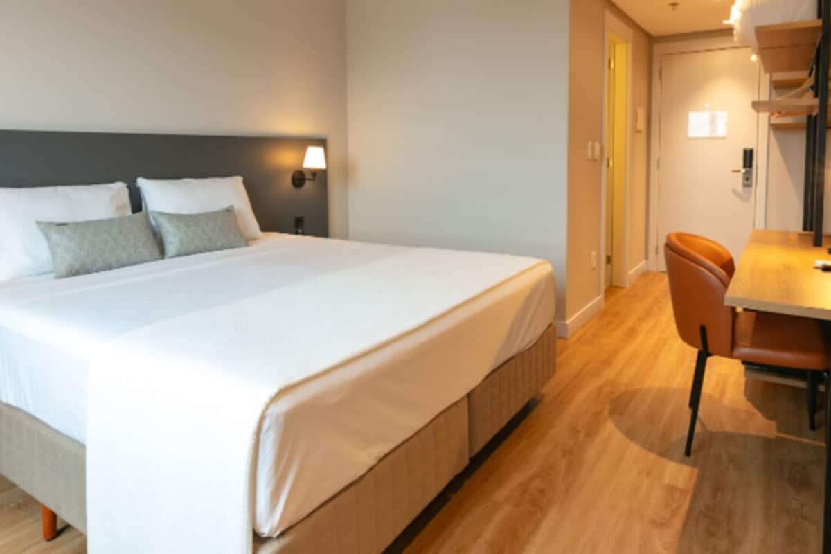Una habitación de hotel con una cama grande, un escritorio y una silla.