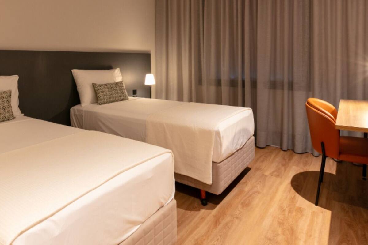 Habitación de hotel con dos camas, un escritorio y una silla.