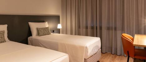 Une chambre d’hôtel avec deux lits, un bureau et une chaise.