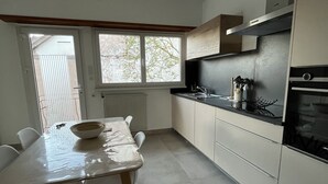 Une cuisine moderne avec une table à manger, des chaises et une fenêtre.