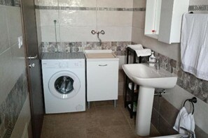 A compact bathroom with a washing machine, a sink, and a cabinet.