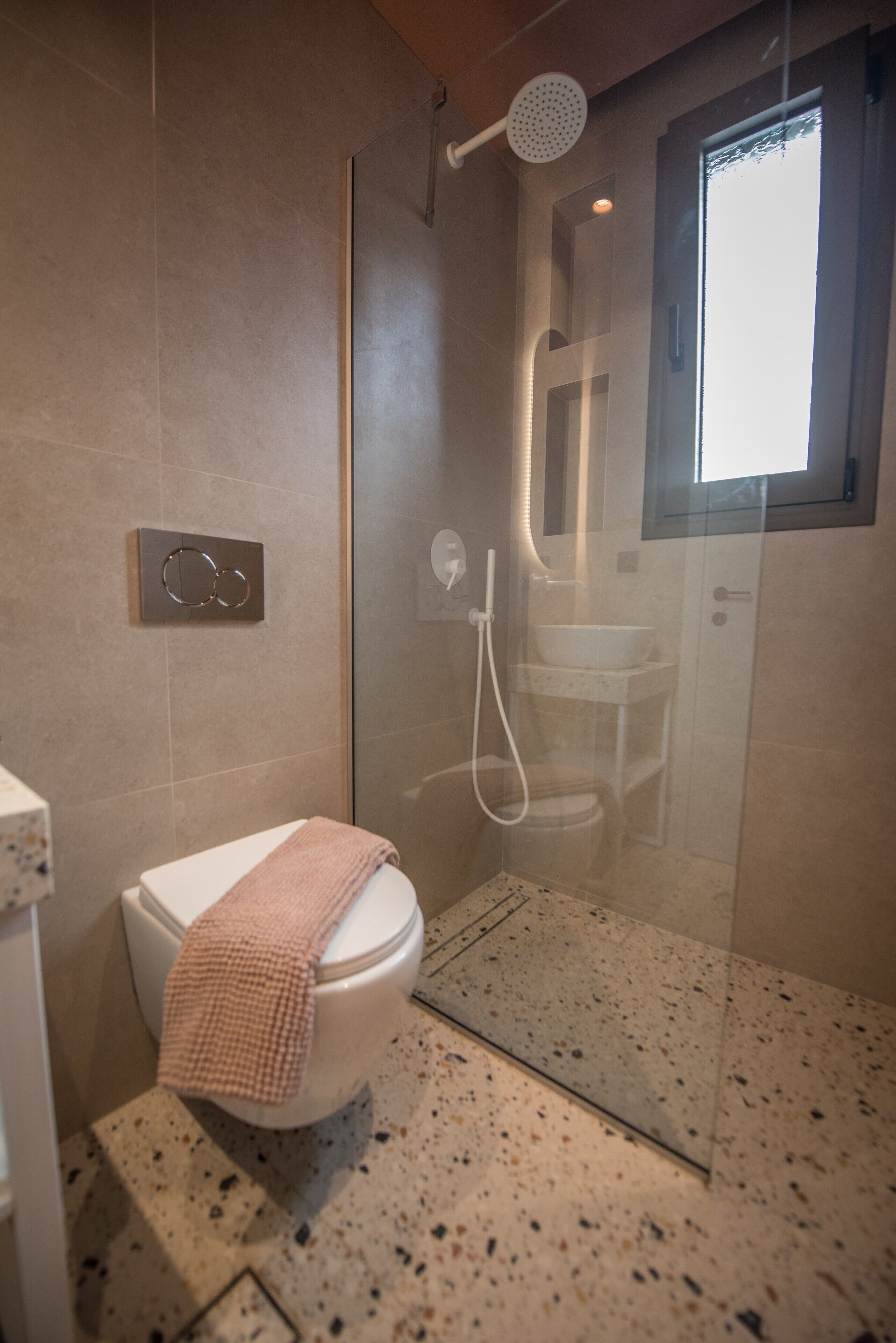 A modern bathroom with a glass-enclosed shower, a toilet, and a sink.