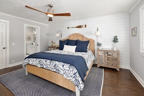 Un dormitorio con cama, mesita de noche, ventilador de techo y cabecera de madera.