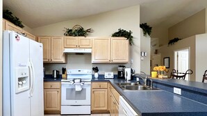 A modern kitchen with wooden cabinets, a white refrigerator, a stove, and a dishwasher.