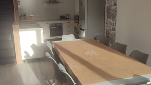 Una cucina moderna con pensili bianchi, un tavolo da pranzo in legno e un frigorifero.