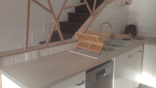 Una cucina moderna con una scala in legno, mobili bianchi e lavastoviglie integrata.