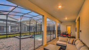 Ein überdachter Patio-Bereich mit Pool, Sitzgelegenheiten im Freien und Blick auf benachbarte Häuser.