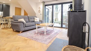 Un salon moderne avec un canapé gris, une table basse en bois et une cheminée noire.