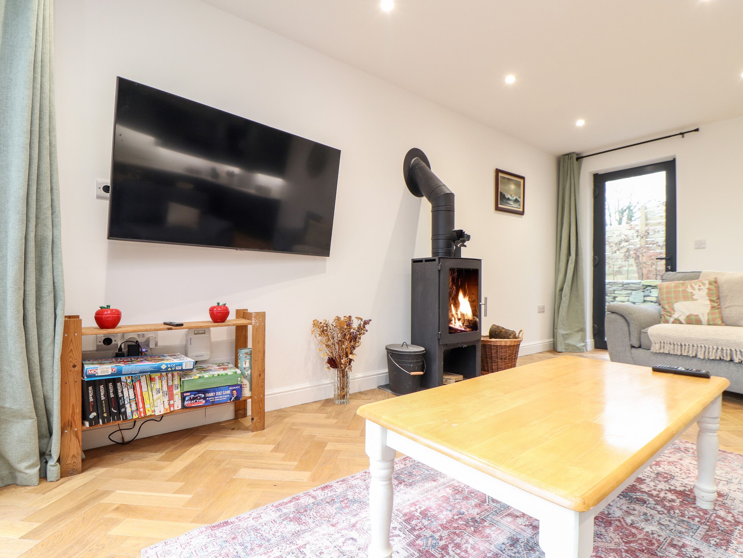 A living room with a flat-screen TV, a wood-burning stove, a bookshelf, and a sofa.