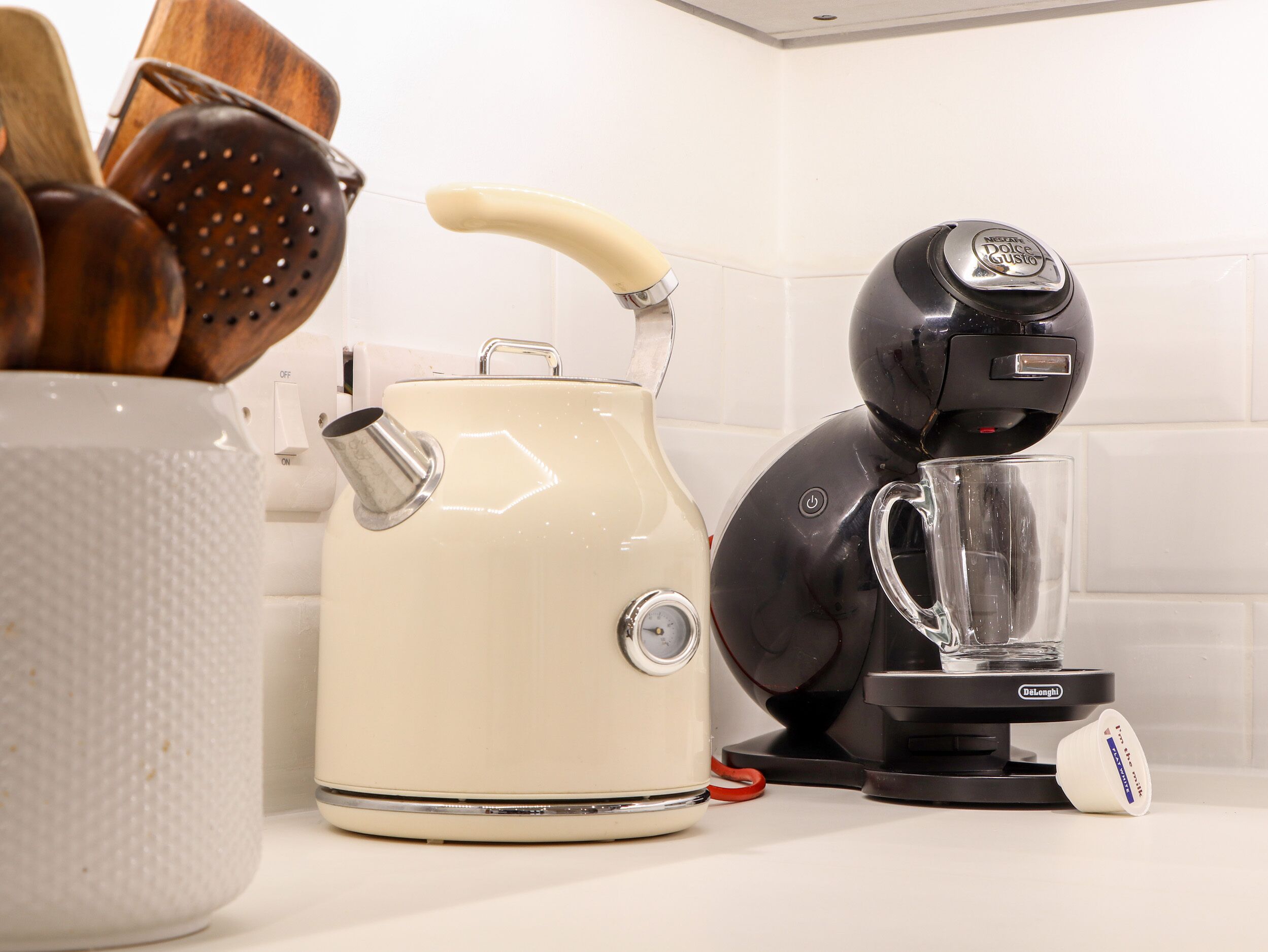 A kitchen with a white kettle, a black coffee maker, and a clear glass pitcher.