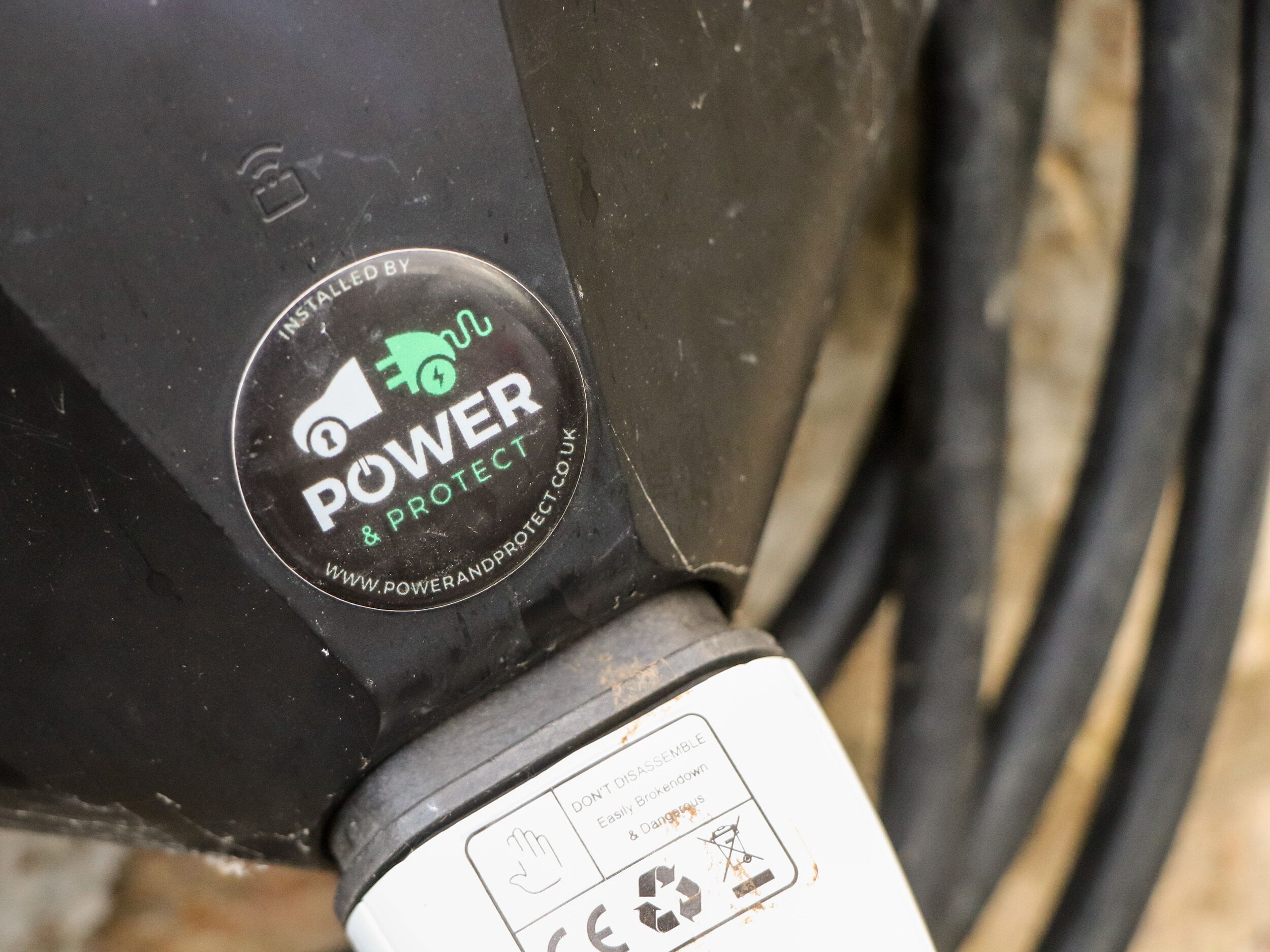 A close-up of a black and white object with a circular logo that reads 'POWER & PROTECT' and a website address.