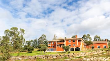 Stunning building with a central entrance and two wings, set amidst a beautifully manicured lawn and lush greenery.