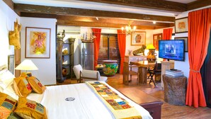 Una habitación de hotel con cama, escritorio, televisor y zona de comedor.