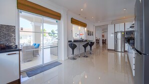 Eine moderne Küche mit Kühlschrank, Mikrowelle und Herd. Eine Glastür führt zu einer Terrasse mit Gartenmöbeln.