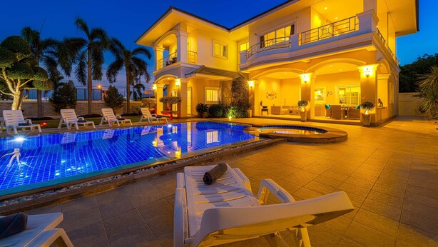 Ein großes, zweistöckiges Haus mit Swimmingpool und Sitzgelegenheit im Freien.