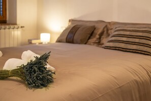 A neatly made bed with a lavender bouquet, a striped pillow, and a bedside lamp. - Cozy apartment with a garden, perfect for families and friends. Near Florence! (Toscana)